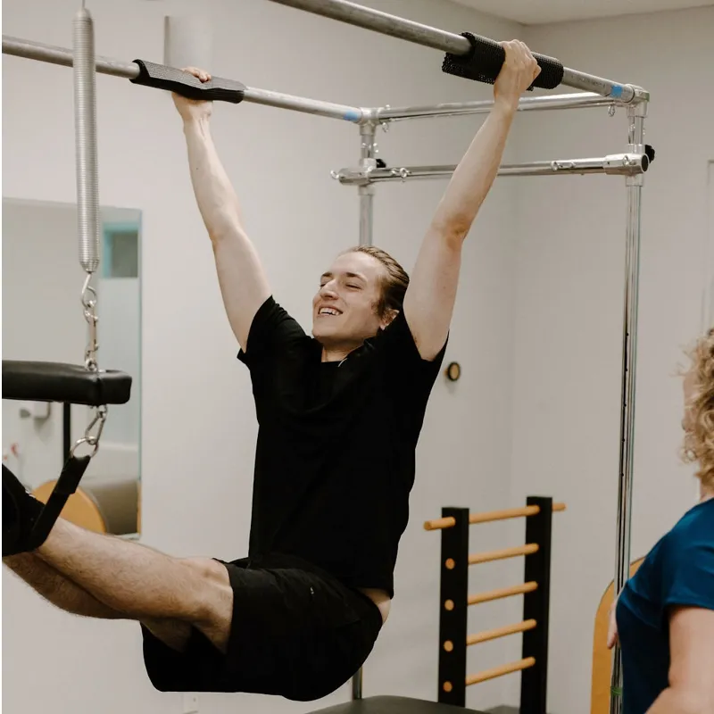 A man training on the spring wall tower at the Momentum Pilates studio