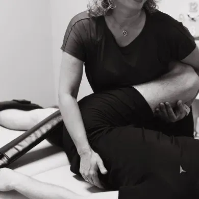 A practitioner stretching a client's leg on a treatment table during a Fascia Stretch Therapy session at Momentum Pilates