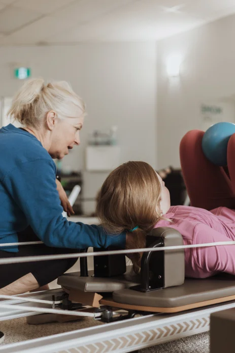 A Momentum Pilates instructor guiding a new client through her first session on the reformer