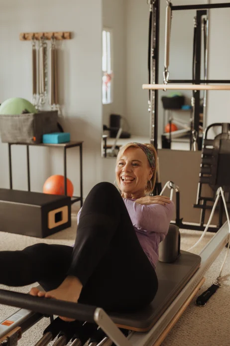 A smiling client mid-workout on the Pilates chair at Momentum Pilates